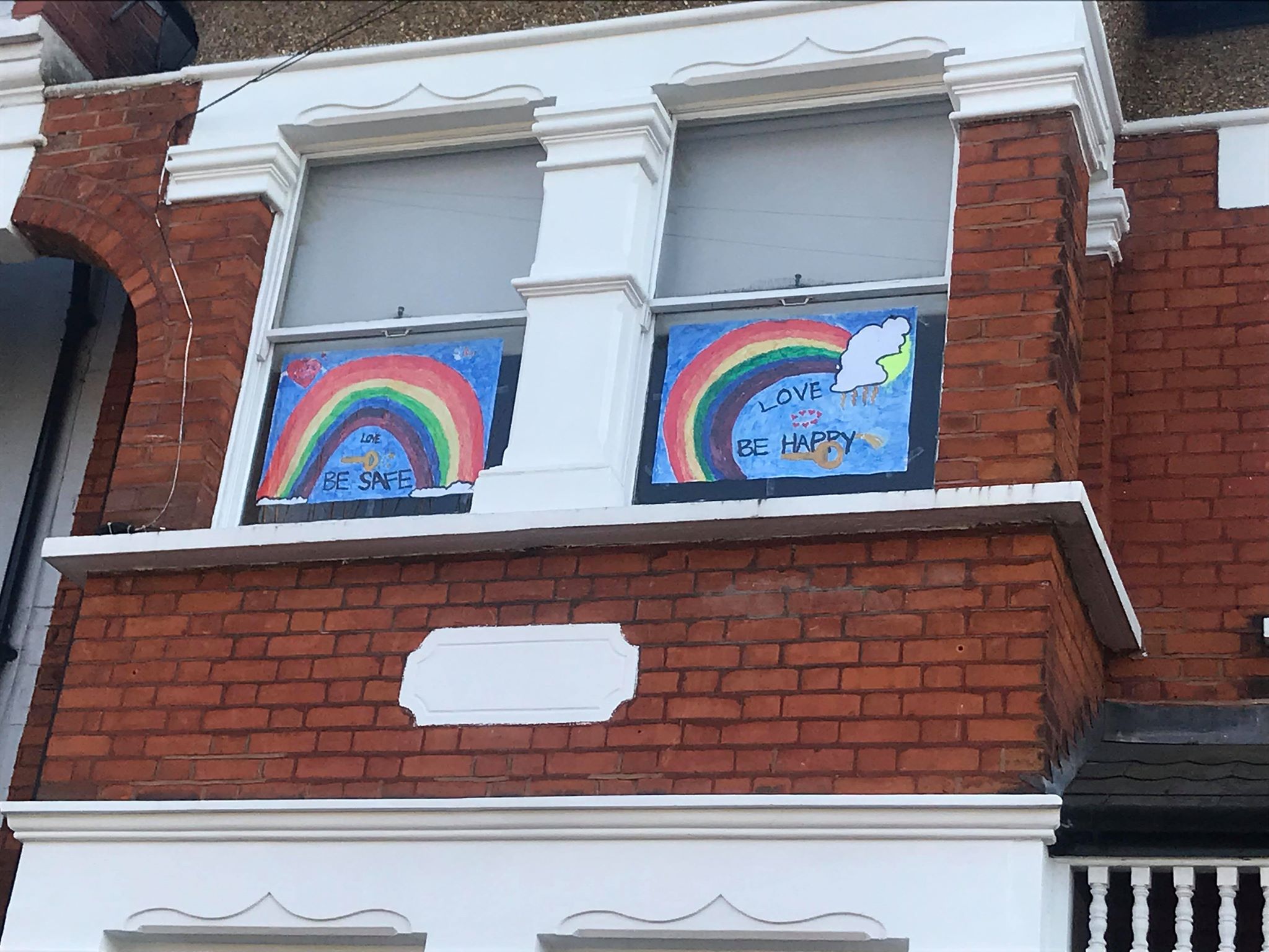 Children's drawings of rainbows stuck on windows for passers by 