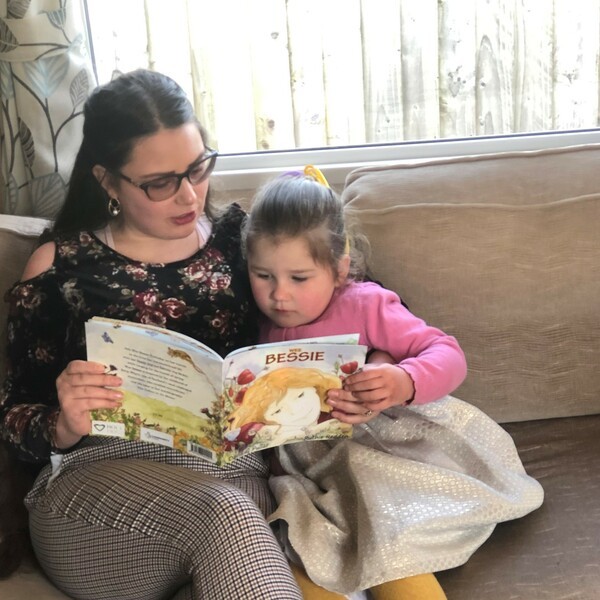 Mother reading to her daughter on the sofa