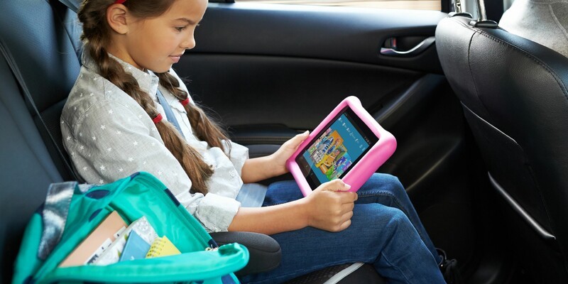 young girl sat in car with iPad 