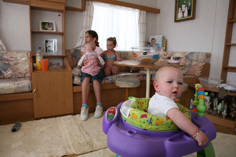 Young women with child on lap and two other children in static caravan 