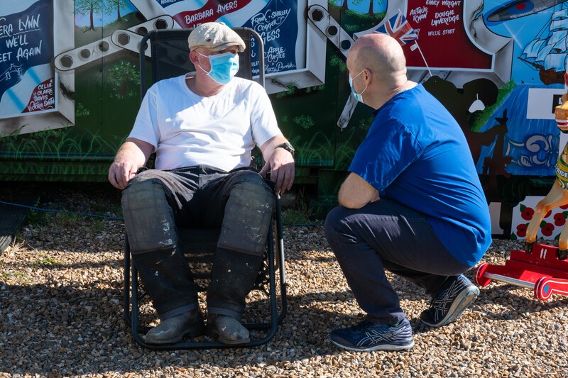 Man on deckchair with covid mask on talking to doctor