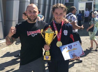 Paris Smith stood next to her coach holding a medal and trophy 