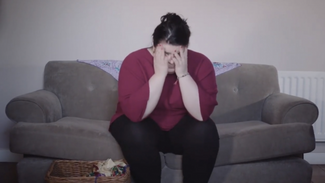 Women sat on sofa with hands over her face looking stressed 