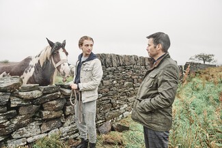 Horse looking over a wall boy and man standing close