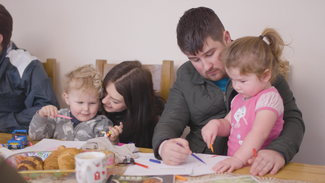 Mother and father supporting child to write