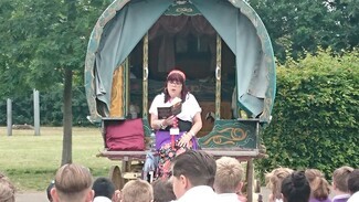 Women sat on wagon reading a book to young children 