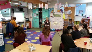 Adult sat in classroom with young people 