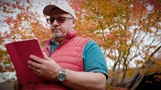 Man with baseball cap and book